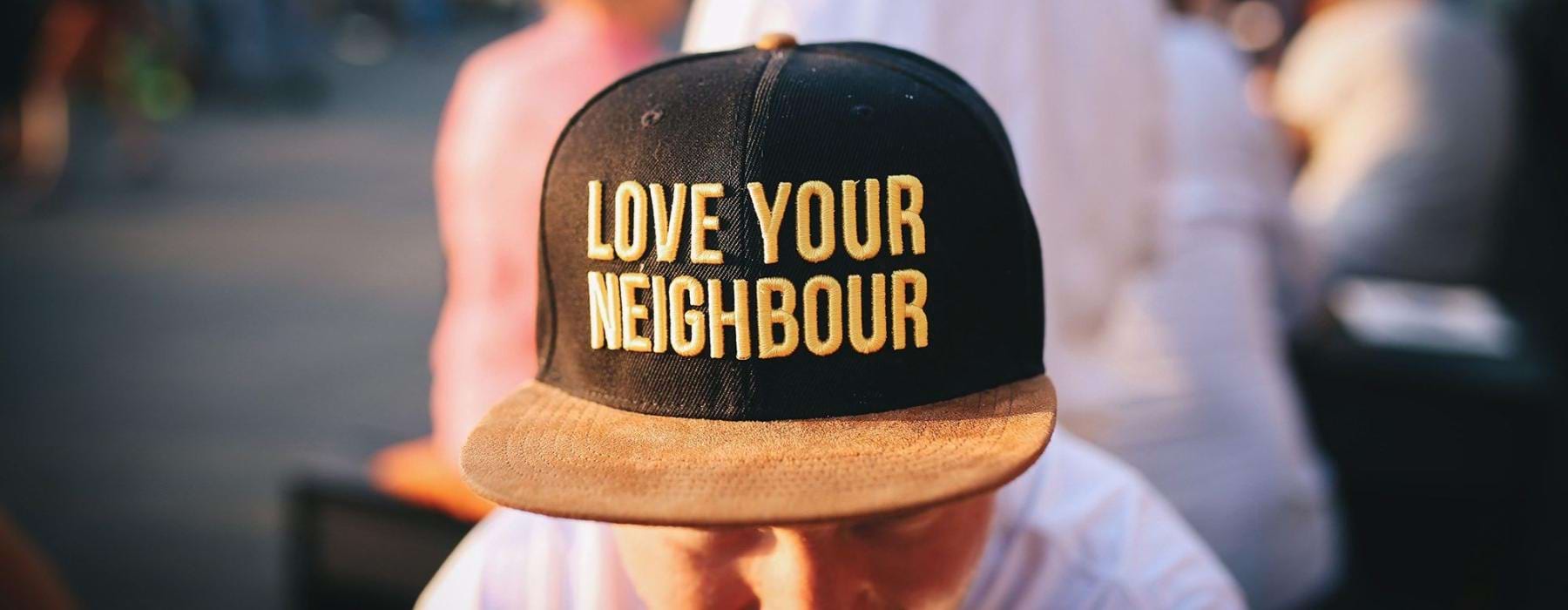 Person wearing "Love Your Neighbour" hat